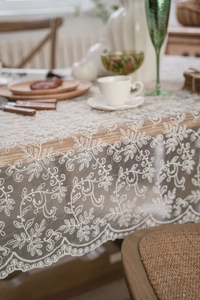 Detailed view of white lace tablecloth showing delicate floral and leaf embroidery texture