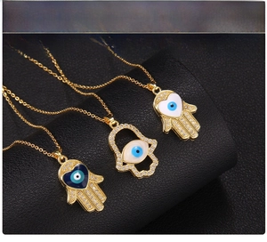 Detailed view of three golden Hamsa Hand necklaces with blue and white Evil Eye charms