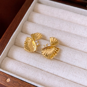 Macro detail of gold leaf earrings with sparkling zircons on soft velvet padding