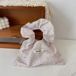 Close-up of floral canvas handbag with ruffled handle and branded Sozakka woven label