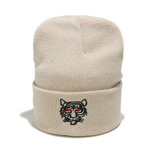 Detailed close-up of tiger head embroidery on a beige knitted beanie hat cuff