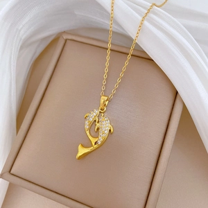 Luxurious gold dolphin pendant necklace with shimmering crystals on a white fabric background