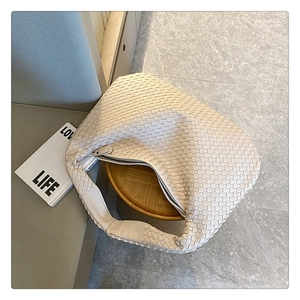 Top view of cream woven shoulder bag on wooden stool with a magazine nearby