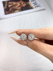Macro shot of a classic sunflower moissanite stud earring held by hand to show size