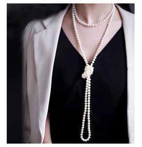 Detailed view of long multilayered white pearl necklace worn on model for styling