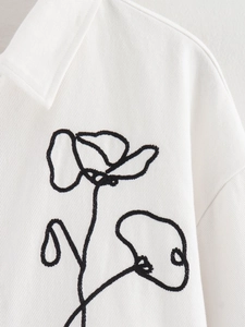 Close-up of black floral embroidery on white twill fabric street style jacket top