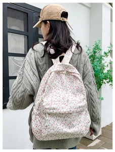 Detailed view of floral canvas backpack with pink flowers on a white background