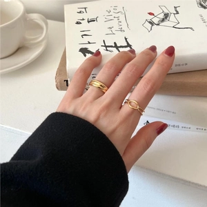 Close-up of gold geometric S925 silver rings layered on fingers over aesthetic book