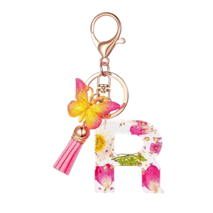 Detail of letter R resin keychain with pink flowers, gold foil, tassel, and butterfly charm