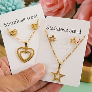 Gold stainless steel jewelry set with heart and star pendants held on display cards
