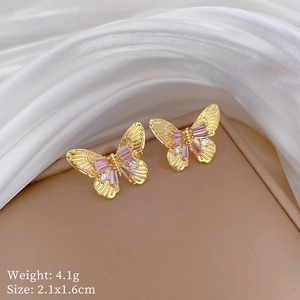 Detail view of gold butterfly earrings with pink crystals and small white diamonds