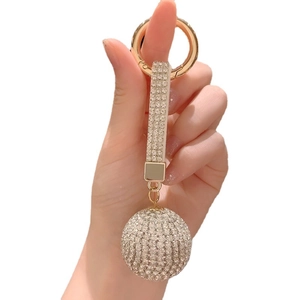 Sparkling crystal ball keychain with rhinestones and gold ring held by hand