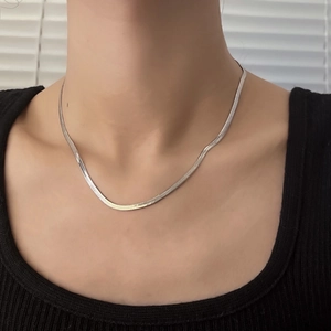 Detail of silver double-layered snake chain necklace with flat metallic weave texture