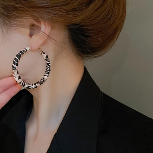 Close-up of model wearing leopard print faux leather hoop earrings with silver pins