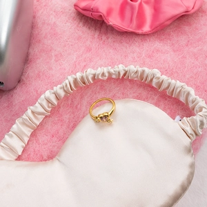 Detailed shot of golden ring with purple heart zircon on soft pink silk fabric