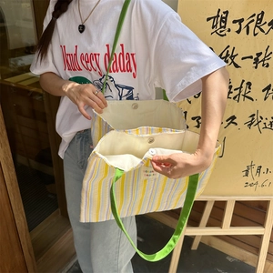 Dettaglio della borsa tote in tela a righe con chiusura magnetica e tracolla verde vivace