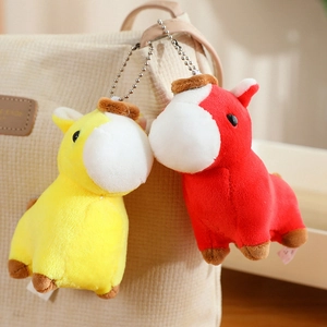 Detail of yellow and red plush horse charms hanging on a corduroy bag with metal chains