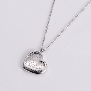 Detail of silver heart pendant with honeycomb cutout design and forever engraving