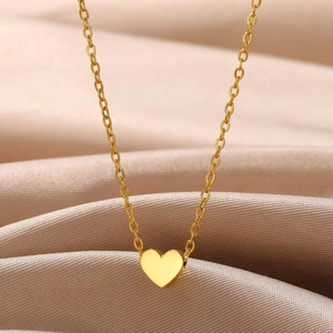 Minimalist gold heart pendant necklace with elegant O-chain on champagne satin fabric