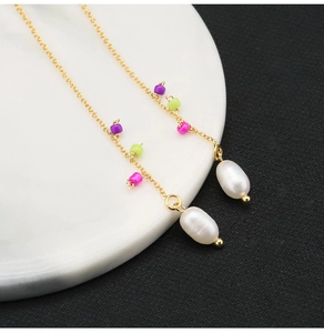 Detailed shot of long gold chain earrings with multicolor beads and white natural pearls