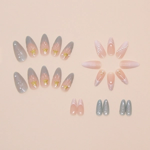 Detail of almond shaped press-on nails with 3D seashells, pearls and gold stars