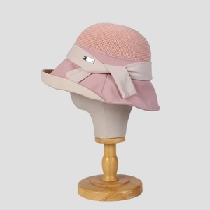 Detail of pink sun hat featuring breathable mesh top and decorative bow with metal tag
