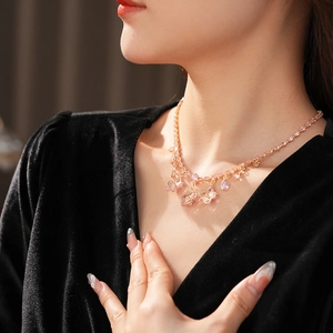 Detail shot of a model wearing a gold necklace with pink zircon flowers and drop pendants