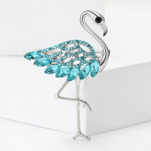 Elegant silver flamingo brooch with blue rhinestones on a white geometric stage