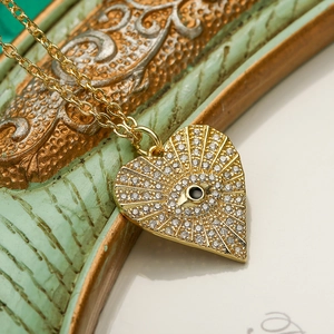 Gold plated heart evil eye necklace with zircon stones on a vintage background