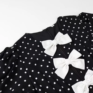Close-up of polka dot dress neckline with white decorative bows and zipper detail
