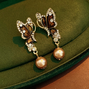 Detail of vintage gold butterfly earrings with brown enamel, crystals and pearls on velvet