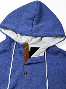Detail of blue textured hoodie with button neckline and white drawstrings close-up view