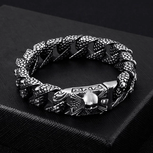 Macro view of silver skull bracelet with scale pattern weave on black textured surface