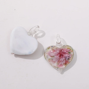 Macro detail of heart-shaped glass pendants with pink floral patterns for DIY jewelry