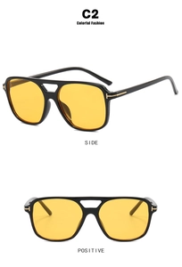 Detail view of square black frames with yellow lenses and golden T-shaped metal hinges