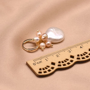 Baroque natural pearl earring on beige silk background with a ruler for size reference