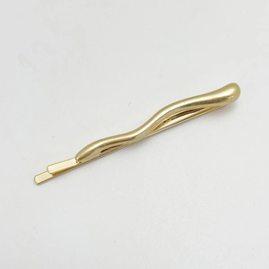 Detailed close-up of a wavy gold alloy hair clip with a polished finish and minimalist style