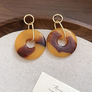 Macro view of amber resin drop earrings with gold metal rings in a vintage aesthetic