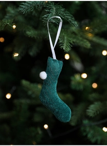 Close-up of a dark green corduroy Christmas stocking ornament with a white pom-pom detail