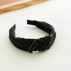 Detail of black knotted fabric headband decorated with gold and black crystal beads