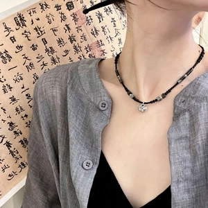 Détail du collier de perles avec pendentif verrou nuage d'argent sur calligraphie