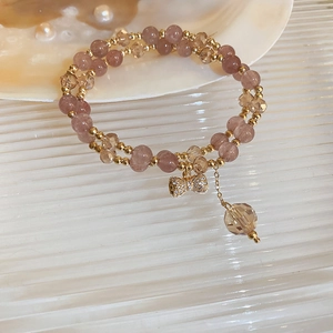 Close-up of double-layer beaded bracelet with pink pearls and a crystal bow charm