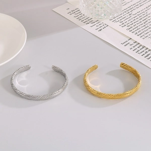 Detail of twisted cable texture on gold and silver stainless steel C-shaped bracelets
