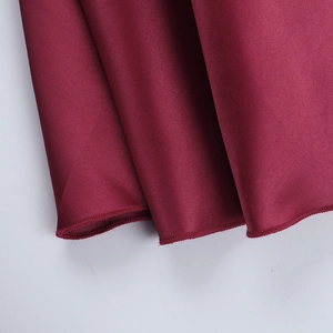 Détail d'une robe en satin bordeaux montrant les plis et la couture de l'ourlet