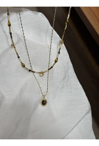 Detail of double-layer gold plated necklace with tiger eye stone pendant and beads