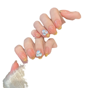 Cat eye peach gradient press-on nails with gold glitter tips and 3D floral accents