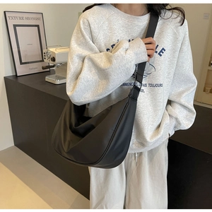 Black nylon dumpling bag shown on model featuring a large capacity crossbody design
