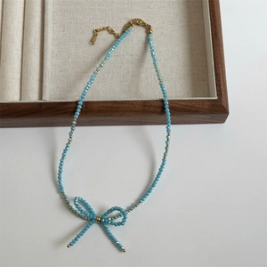 Detailed view of sky blue beaded necklace with handmade bow knot and gold clasp