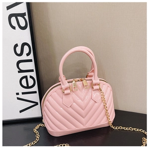 Detailed macro view of pink jelly bag with V-shaped quilting and gold metal chain strap
