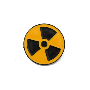 Detailed view of yellow and black round metal pin with vintage radiation symbol